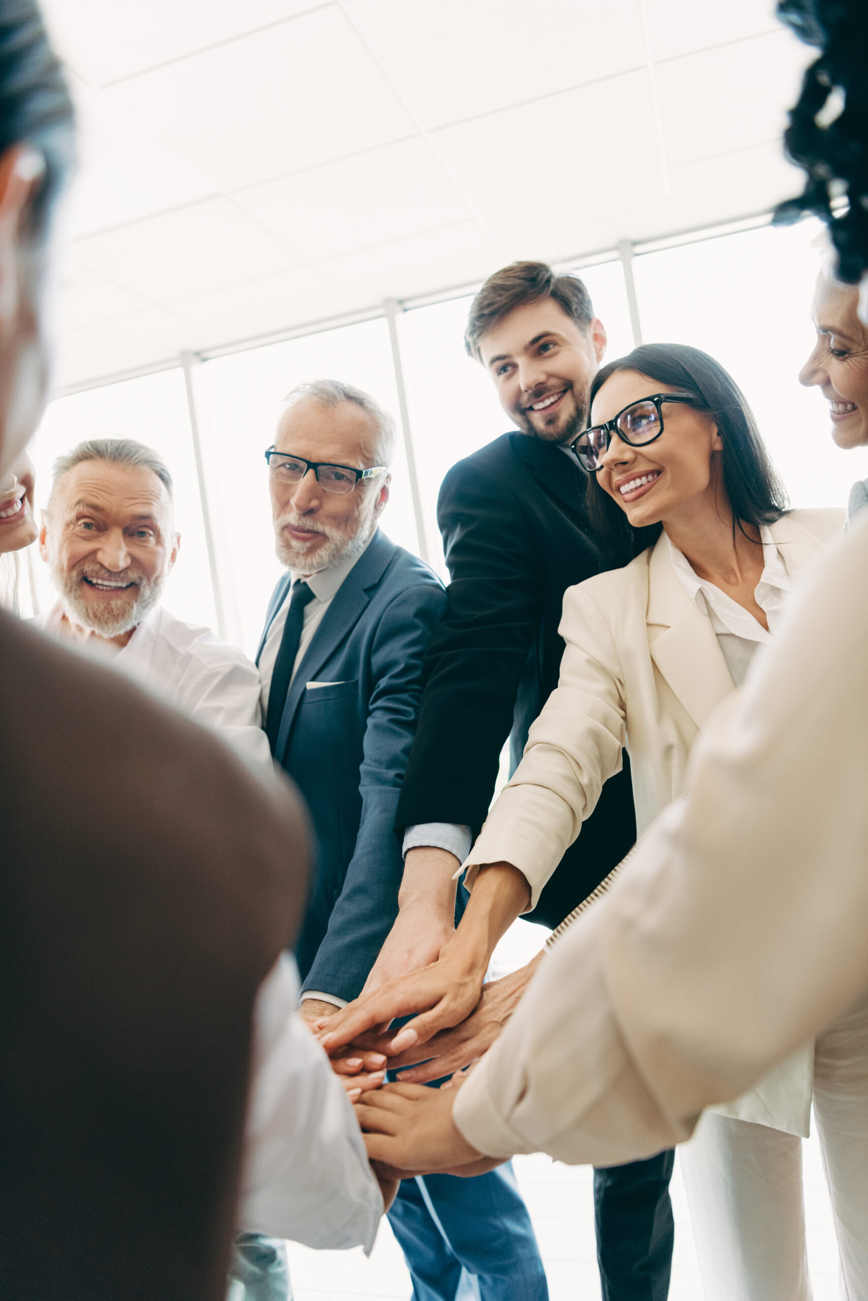 Team von Mitarbeitenden legt gemeinsam die Hände übereinander als Symbol für Zusammenarbeit, Vertrauen und Unternehmenskultur.